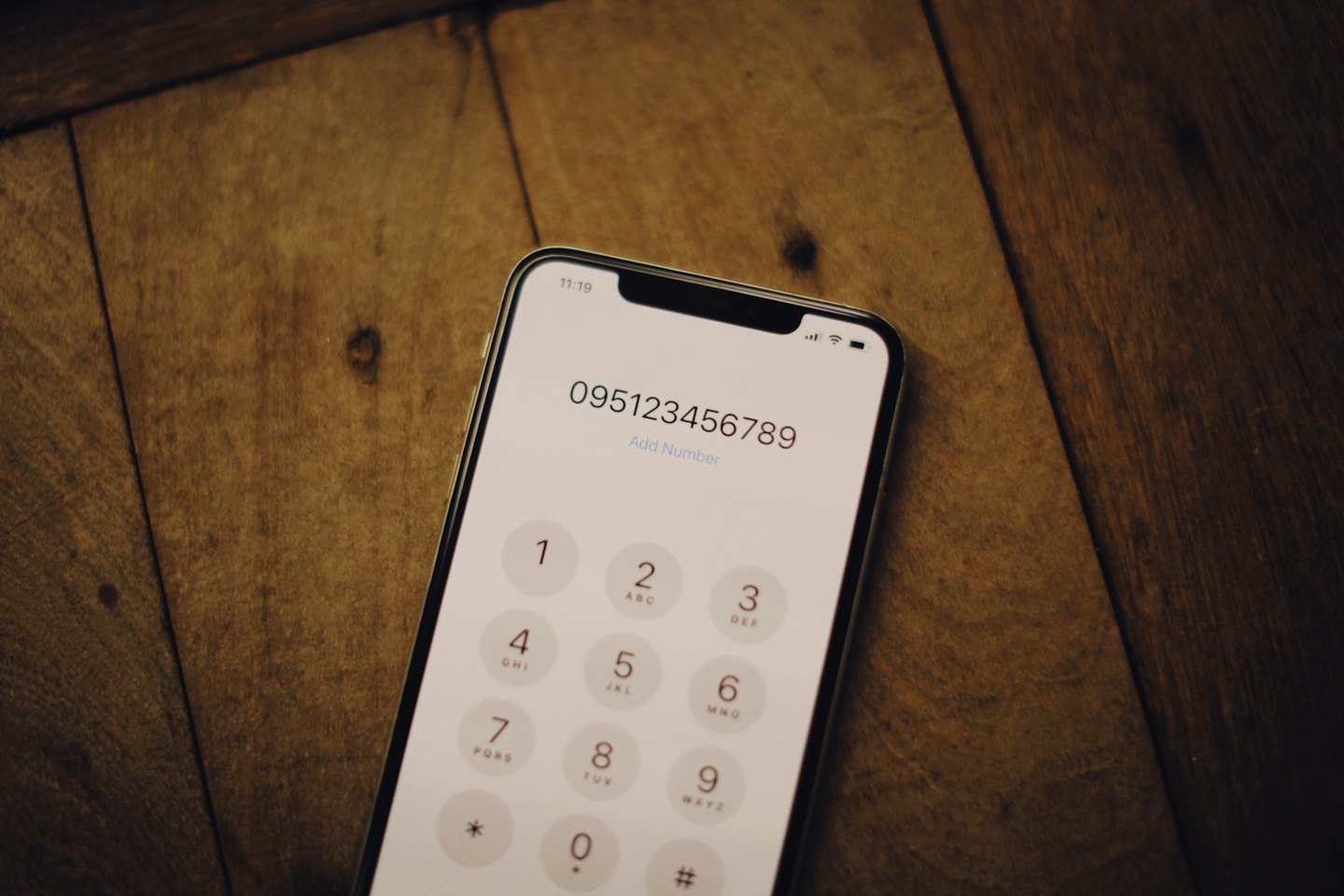 Smartphone screen showing a dial pad on a wooden desk.
